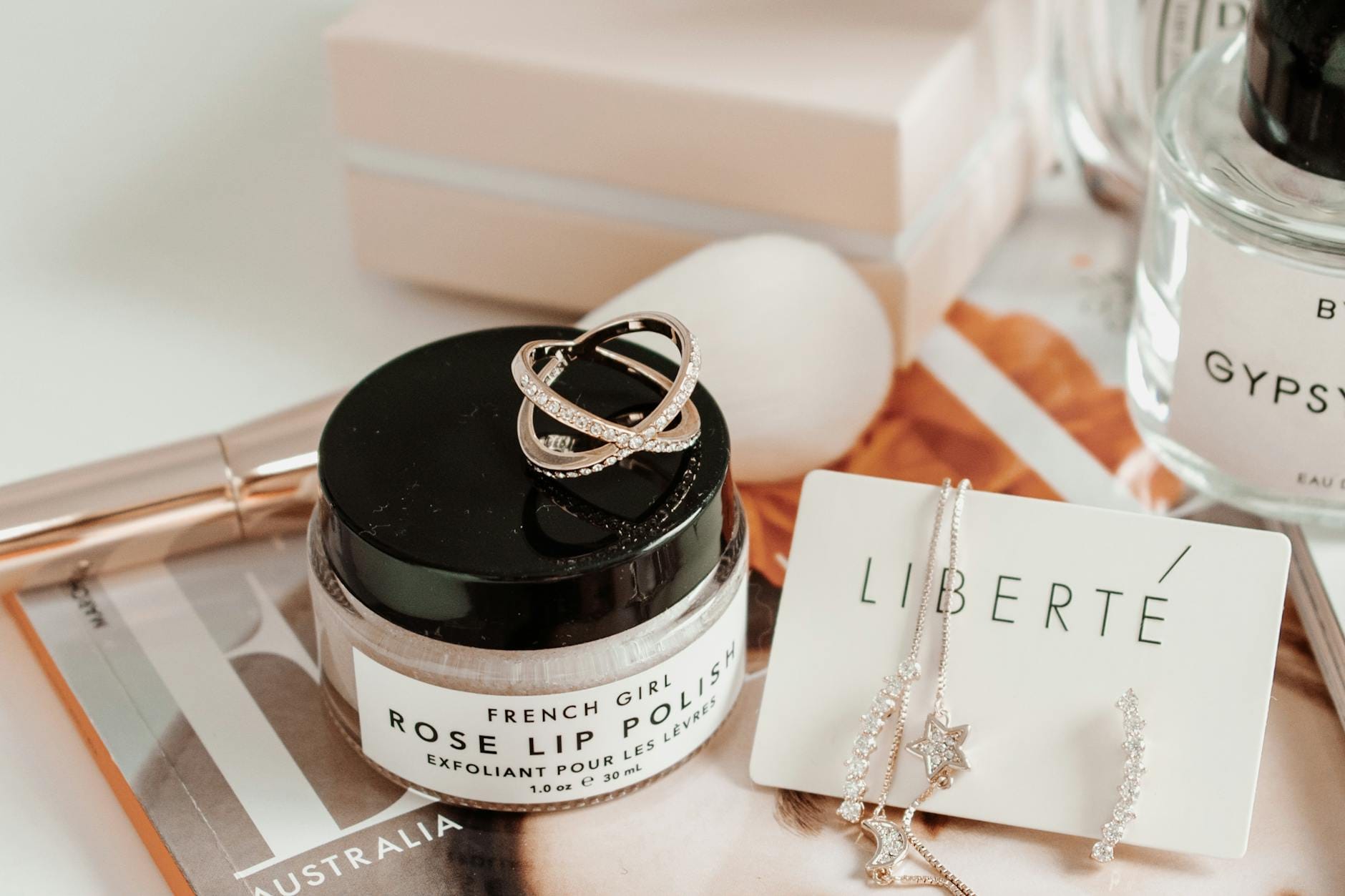 Różowe błyszczyki do ust i biżuteria ułożone na eleganckim stoliku