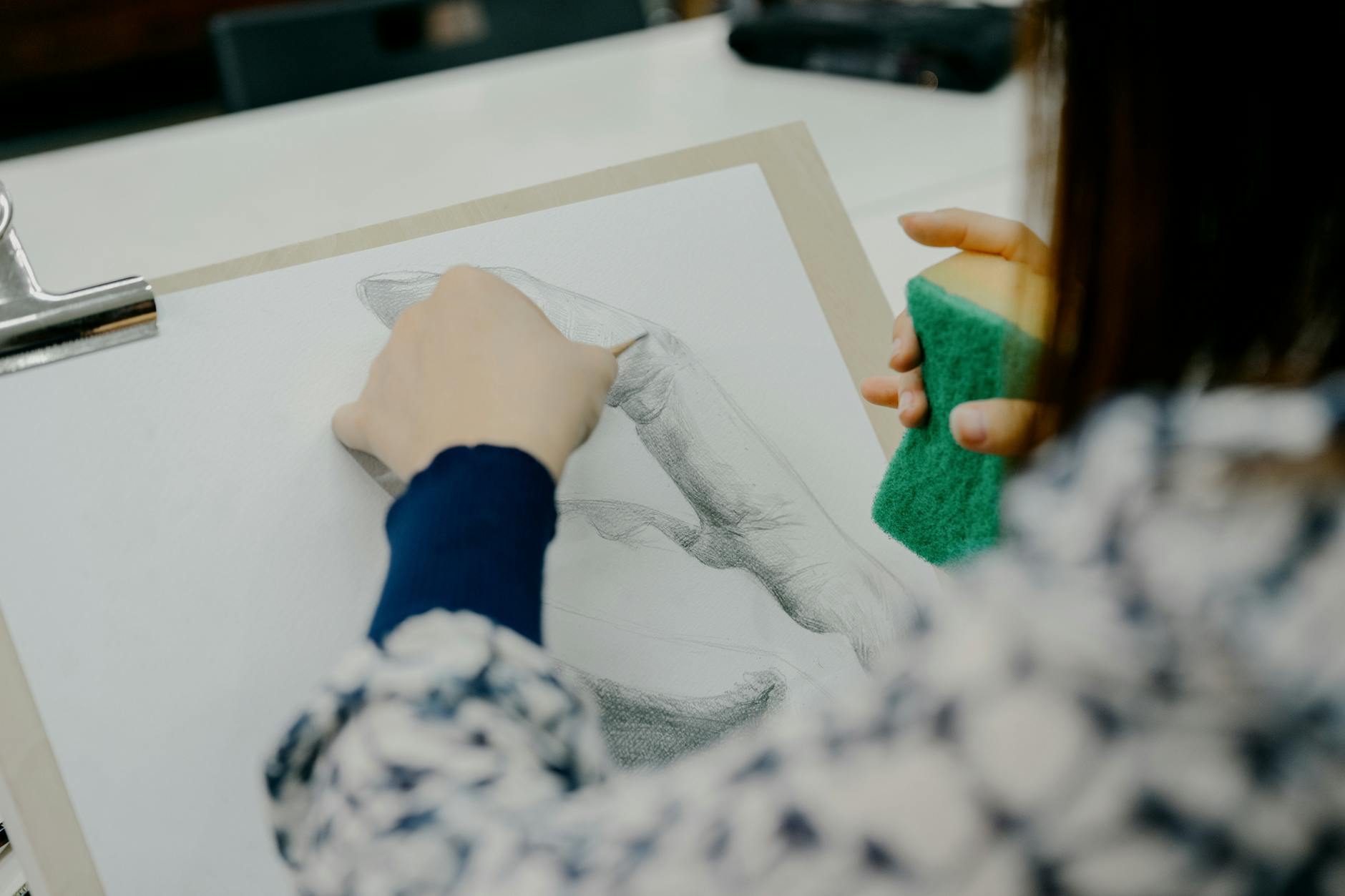 Uczeń rysuje dłoń ołówkiem w pracowni rysunku