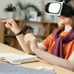 Nastolatek w goglach VR uczy się historii przy biurku w domu