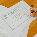 Rodzic podpisujący dokumenty dotyczące dziecka na biurku
