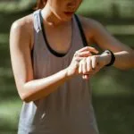 Kobieta w stroju sportowym sprawdza smartwatch podczas treningu na zewnątrz