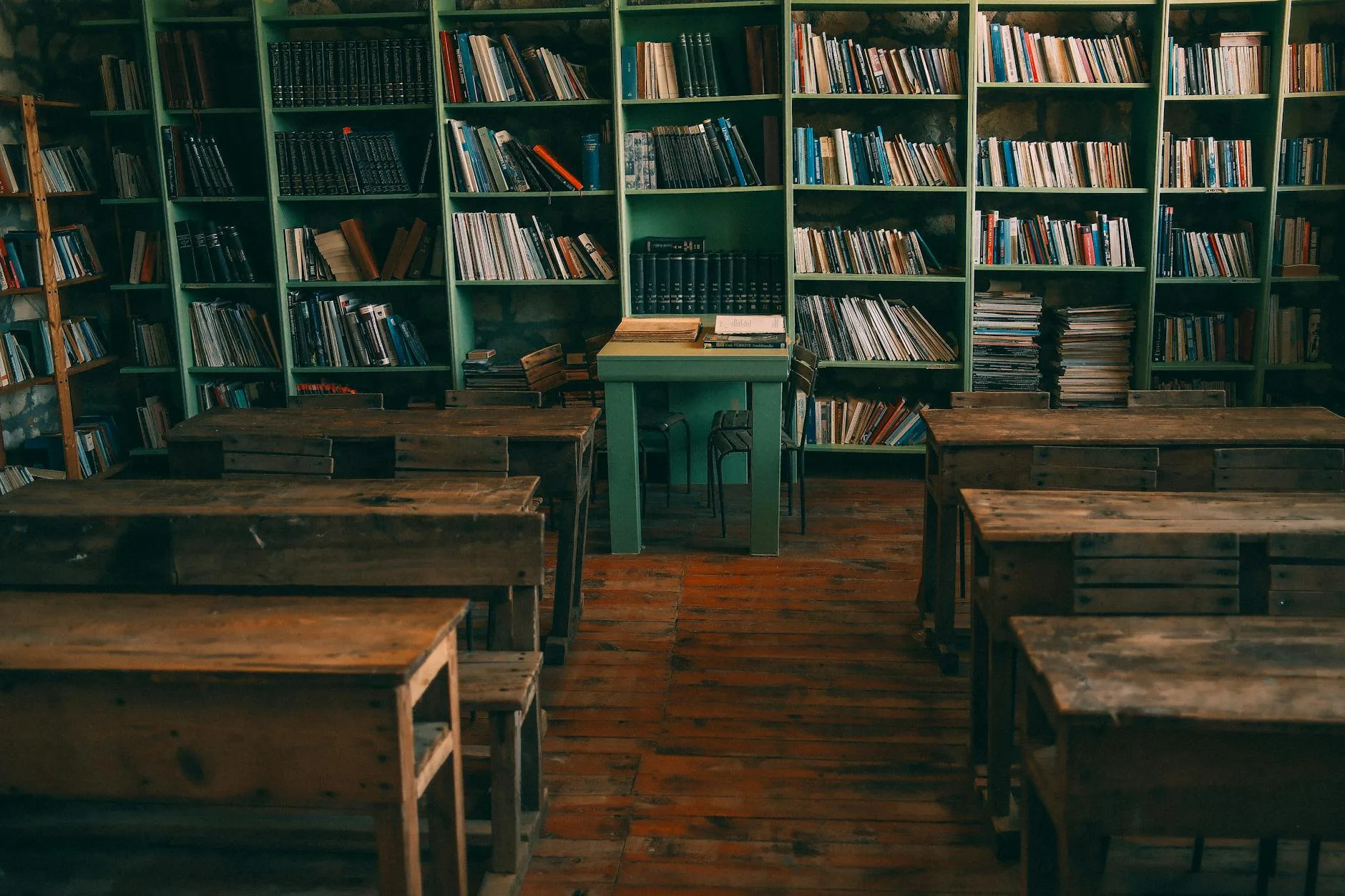 Stara szkolna klasa z drewnianymi ławkami i regałami pełnymi książek